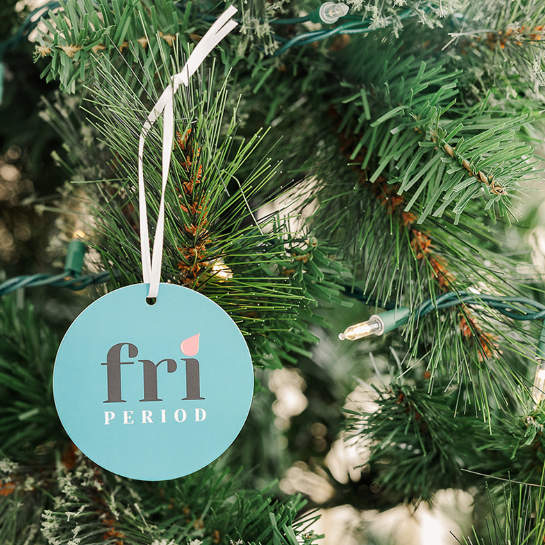 Fri Period branded gift tag hanging on branches of a Christmas tree